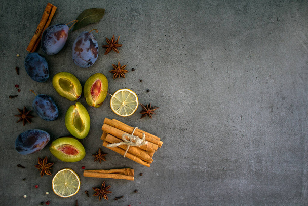 Hůlky skořice, švestky a sušený citron na tmavě šedém texturovaném pozadí s kopírovacím prostorem.  - Fotografie, Obrázek