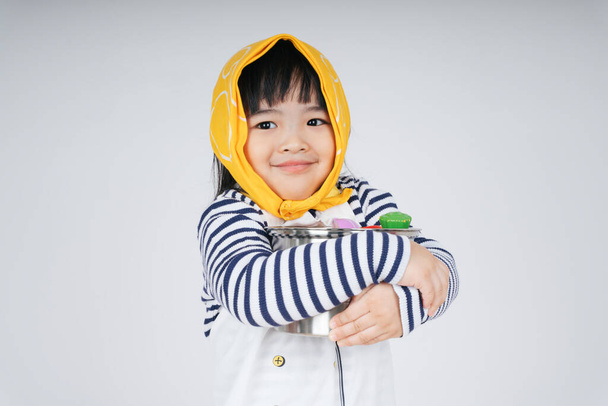 dość Azji tajski dzieciak grać rolę jako kelnerka noszenie żółty bandaż przytulanie garnek izolat na białym tle. - Zdjęcie, obraz