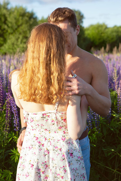 portrait of a man and woman in love gently kissing on a blooming lupine field on a bright Sunny day - Fotografie, Obrázek