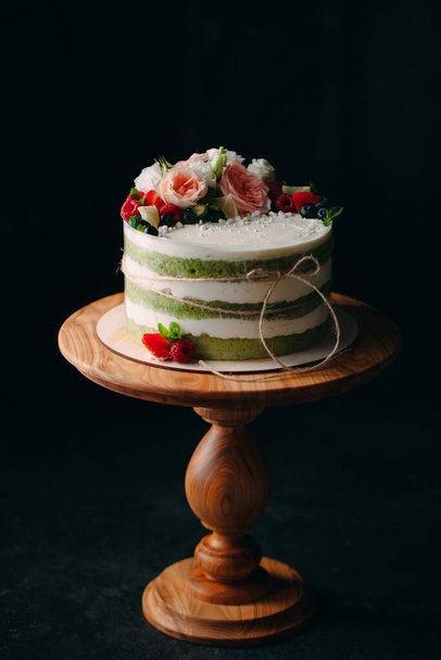 Cake is decorated with flowers on a dark background. - Photo, image