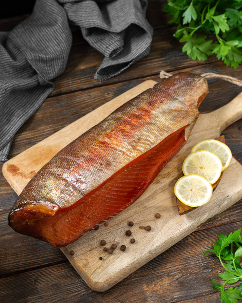 Smoked fish trout. Whole Smoked trout on the serving Board. Smoked trout lay on the wooden kitchen table. Smoked fish close up - Foto, imagen