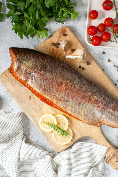 Smoked fish trout. Whole Smoked trout on the serving Board. Smoked trout lay on the light gray kitchen table. Smoked fish close-up - Fotoğraf, Görsel
