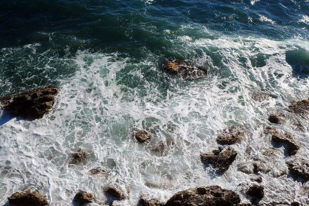 Óceánhullám háttér törés tengervíz sziklás part durva tengerek türkiz víz gradiens hab. Nagy hullámok a nyílt tengeren. Nyári monszun. Egy tengeri hullám fehér címerét. - Fotó, kép