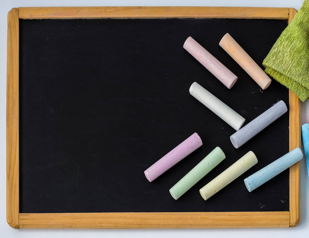 Le matite colorate sono posizionate su un tavolo da disegno nero per bambini con una copia dello spazio. - Foto, immagini