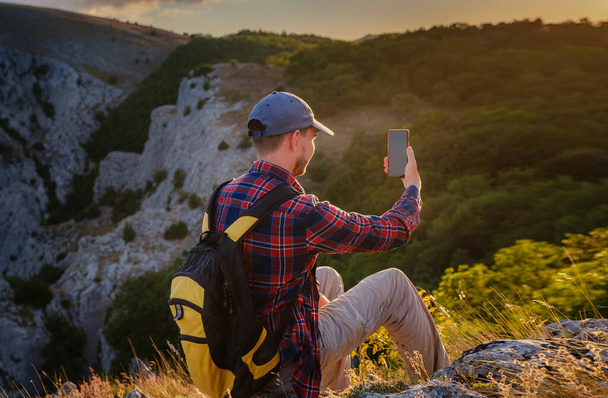 Silny człowiek turysta robi zdjęcia ze smartfonem na szczycie góry. Cudowny świt. Koncepcja działalności i dostępność łączności ruchomej - Zdjęcie, obraz