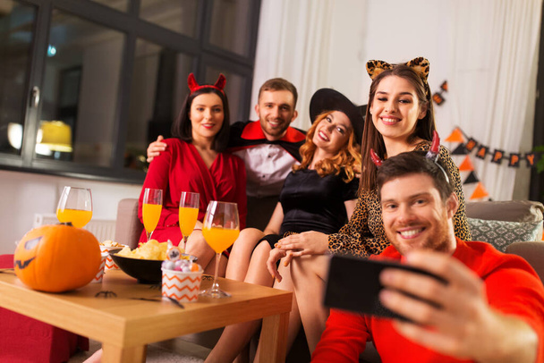 happy friends in halloween costumes taking selfie - Foto, Imagen