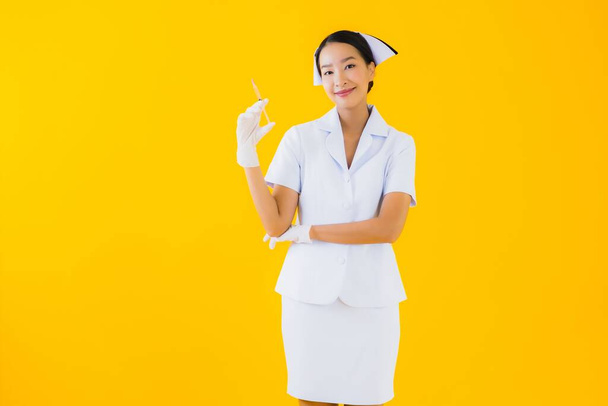 Portrait belle jeune femme asiatique thai infirmière porter gant sur fond jaune isolé
 - Photo, image