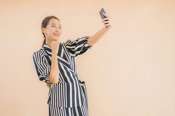 Muotokuva kaunis nuori aasialainen nainen älypuhelimella ruskealla taustalla - Valokuva, kuva