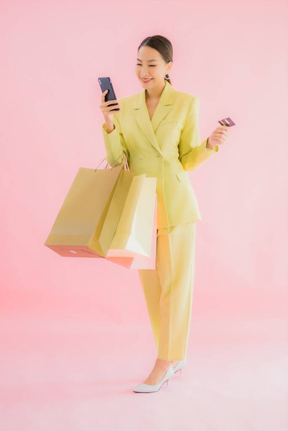 肖像画美しい若いアジアのビジネス女性でショッピングバッグ上の色隔離された背景 - 写真・画像