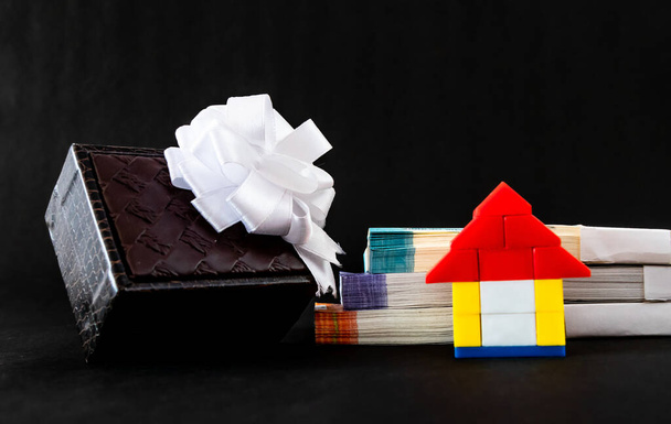 Primer plano de ángulo bajo de una casa de juguete, dinero y caja de regalo que muestra el concepto de casa de regalo - Foto, imagen