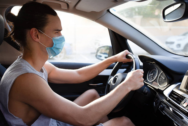 Grave cercando giovane uomo alla guida mentre indossa una maschera viso medico usa e getta. - Foto, immagini