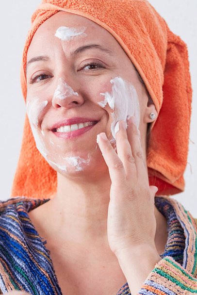 Een vrouw die een gezichtsmasker aanbrengt en plezier heeft - Foto, afbeelding