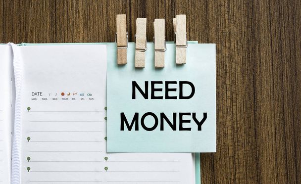 Need Money notities papier en een wasknijpers op houten achtergrond - Foto, afbeelding