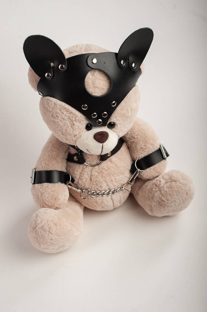 oso de juguete vestido con cinturones de cuero arnés accesorio para juegos de bdsm sobre un fondo claro - Foto, Imagen