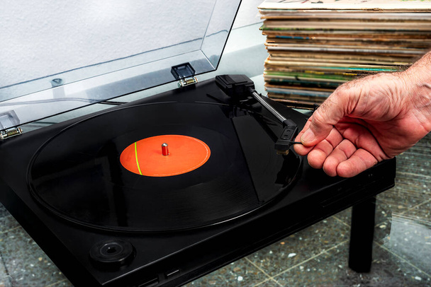 hand plaatsen van een vinyl plaat op een platenspeler met een stapel v - Foto, afbeelding