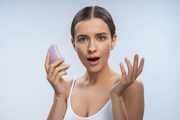 Astonished lady with a sonic facial cleansing brush - Photo, image