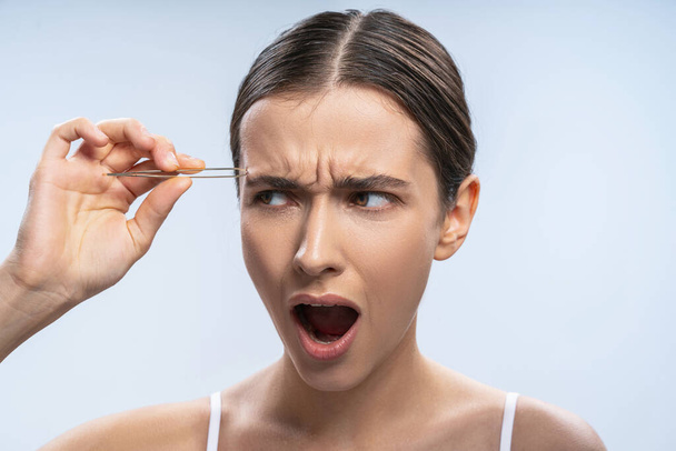 Irritated young woman performing a beauty procedure - Foto, Imagem