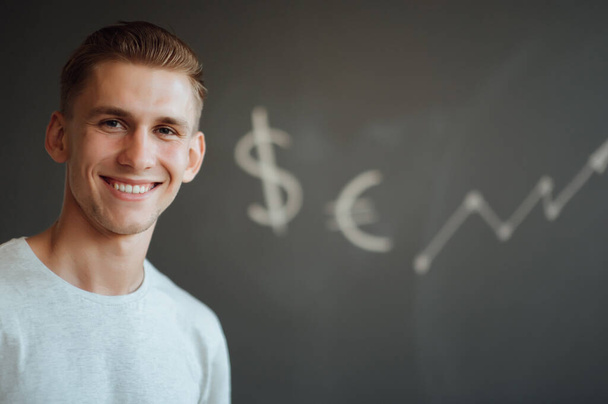 Smiling young man holding a folder with documents in his hands on the background of drawn business sketches.Investment concept, currency - Фото, зображення