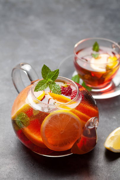 Traditional fruit tea in teapot with lemon, berries and mint. View with copy space - Photo, Image