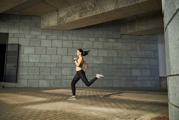 Active female person running quickly on the sidewalk - Fotografie, Obrázek