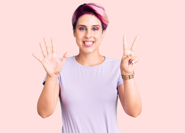 Νεαρή όμορφη γυναίκα με ροζ μαλλιά φορώντας casual ρούχα δείχνει και δείχνει προς τα πάνω με τα δάχτυλα αριθμό επτά, ενώ χαμογελά αυτοπεποίθηση και χαρούμενος.  - Φωτογραφία, εικόνα