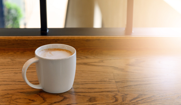 white coffee cup with hot cappuccino coffee on wooden table in coffee cafe. copy space for adding text - Fotó, kép