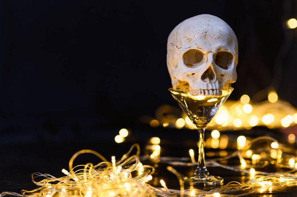 ludzka czaszka na pustym kieliszku do picia i dekoracja diodami LED z wolną przestrzenią do kopiowania tekstu. wystrój na imprezę - Halloween tle - Zdjęcie, obraz