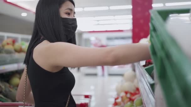 független ázsiai nő visel arc maszk választható kínálat polcon, előtt áll élelmiszer polc nézi a termék belül kiskereskedelmi szupermarket, covid19 corona vírus világjárvány, kiválasztó élelmiszer - Felvétel, videó