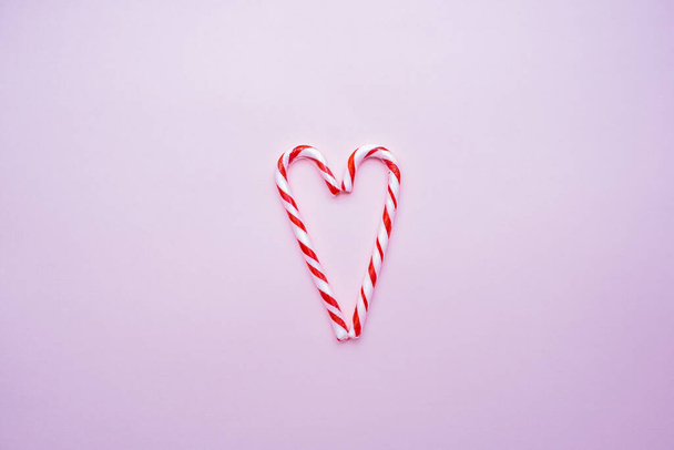 white and red candy canes in the form of a heart on a pink background, copy space - Photo, Image