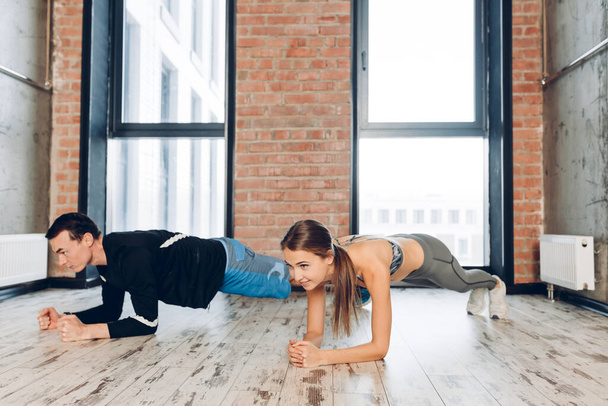 positive sportswoman and sportsman is performing plank - Valokuva, kuva