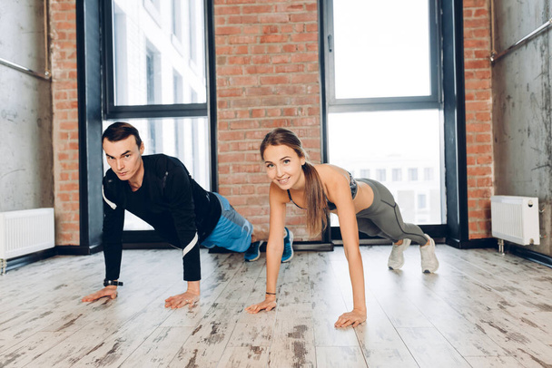Beautiful young woman and handsome man doing some push ups at gym - Fotografie, Obrázek