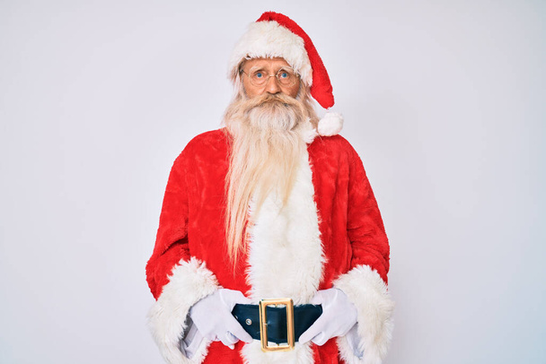 Alter älterer Mann mit grauen Haaren und langem Bart im Weihnachtsmann-Kostüm mit Hosenträgern, deprimiert und ängstlich, weinend, wütend und ängstlich. Traurige Miene.  - Foto, Bild