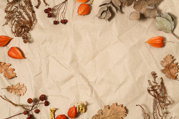 Autumnal leaves and berries on brown paper background - Фото, изображение