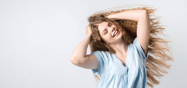 Portrait of attractive carefree european girl, tilting head up and shaking curly hair. Living life to fullest. Having fun and being amused. Copy space for your text - Foto, afbeelding