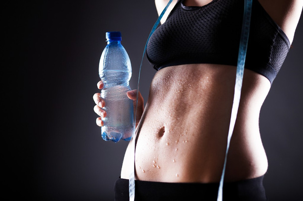 Woman after exercise with measuring tape and water bottle - Valokuva, kuva