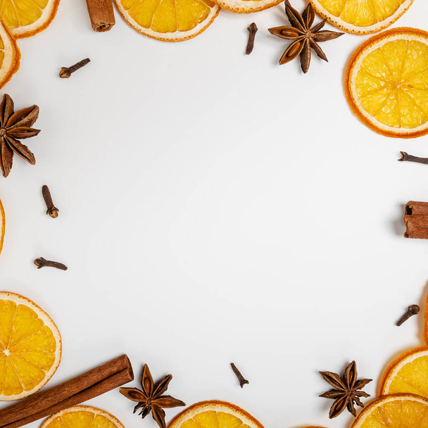 Christmas spices, creative frame. Dry oranges, anise, cloves and cinnamon on the white background with copy space - Zdjęcie, obraz
