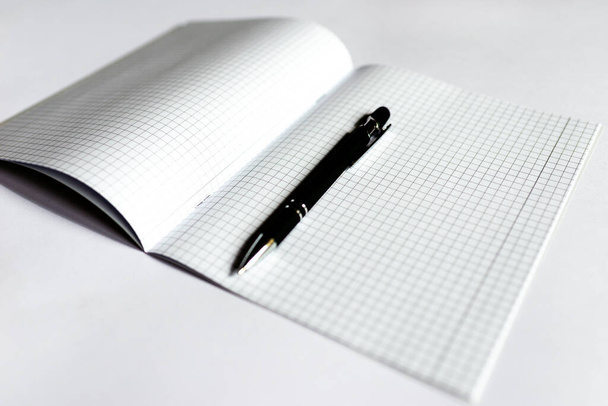 Top view Geruit notitieboekje met een zwarte pen op een witte achtergrond. Plaats voor tekst.Kopieer ruimte.Banner advertentie. - Foto, afbeelding