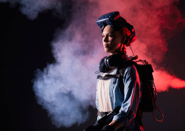 Beautiful woman in futuristic clothes over dark background with smoky - Zdjęcie, obraz