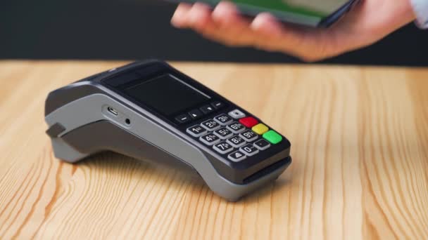 Contactless payment with smartphone with green mock-up screen. Wireless payment concept. Close-up, woman using smartphone cashless wallet NFC technology to pay order on bank terminal. - Footage, Video