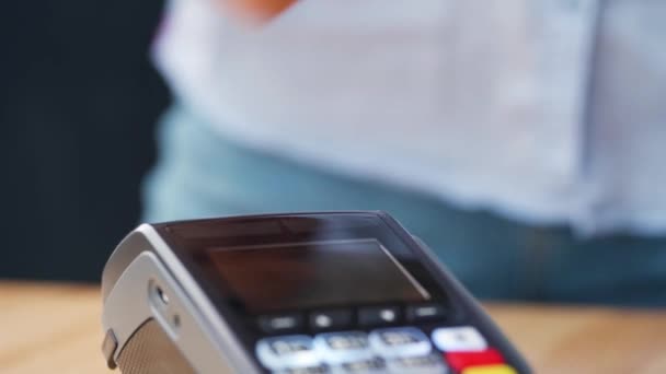 NFCクレジットカード決済。NFC技術と非接触クレジットカードで支払う女性。無線資金取引だ。ワイヤレス決済 - 映像、動画