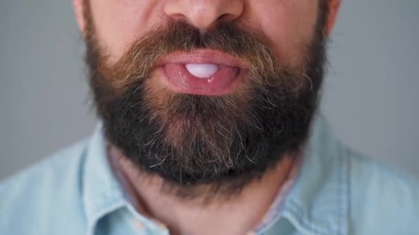 Close-up of a bearded mans mouth chewing chewing gum. Man blowing out a bubble of bubble gum - Footage, Video