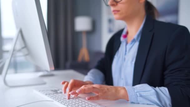 Mujer con gafas escribiendo en el teclado de un ordenador. Concepto de trabajo remoto. - Metraje, vídeo