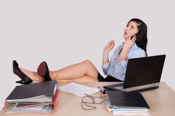 Young female office worker with feet on desk - Fotoğraf, Görsel