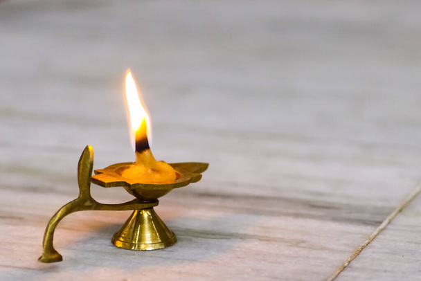 a brass oil lamp being lit at a temple during worship - Photo, Image