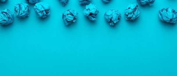 Top view of blue crumpled paper balls over turquoise blue background with copy space and upside composition. Brainstorming concept with blue crumpled office paper. - Fotó, kép