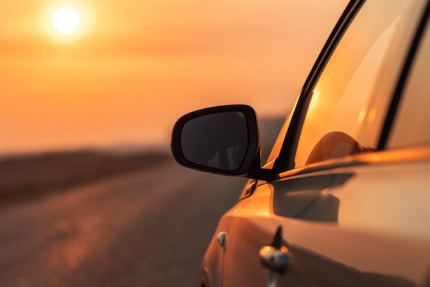 Side view mirror of car on road in autumn sunset for travel, car insurance or roadside assistance concept, selective focus - Foto, Imagen