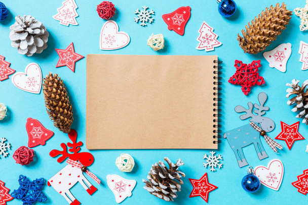 Bovenaanzicht van notebook omgeven met Nieuwjaar speelgoed en decoraties op blauwe achtergrond. Kerstconcept. - Foto, afbeelding