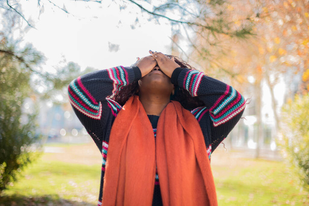 krásná Afroameričanka s dlouhými vlasy na sobě barevný svetr uzavření tvář v podzimním parku   - Fotografie, Obrázek