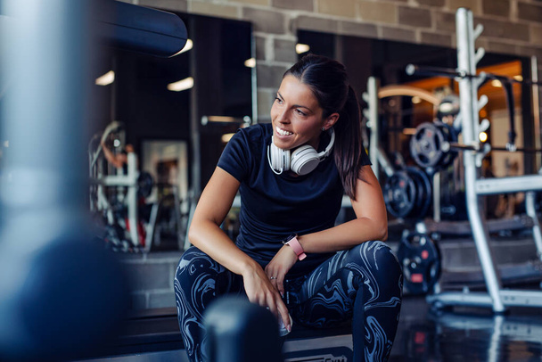 Fit young woman resting after workout or exercise in fitness gym - Photo, image