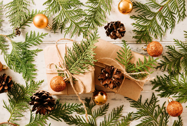 2 cajas con regalos para ramas verdes de thuja, conos, bolas doradas de Navidad sobre un fondo de madera blanca, ramas de coníferas - Foto, imagen